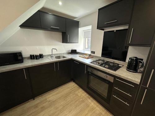 a kitchen with black cabinets and a sink at St Malcolms Wynd in Angus