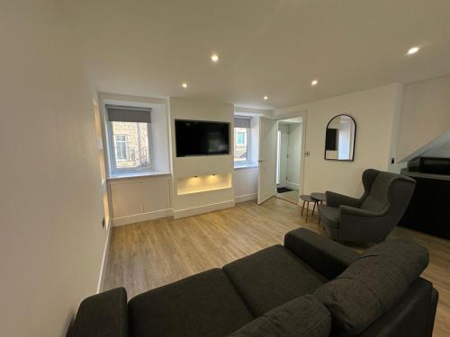 a living room with a couch and two chairs and a flat screen tv at St Malcolms Wynd in Angus