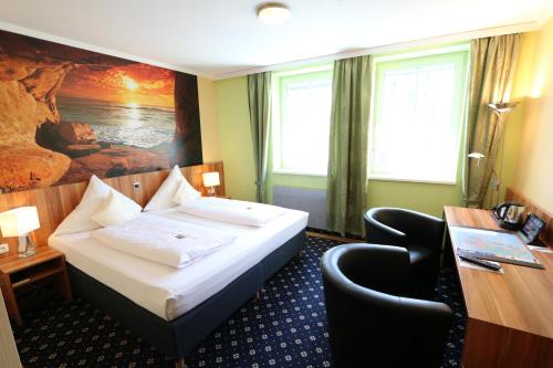 a hotel room with a bed and a desk at Hotel Deutscher Hof in Babenhausen