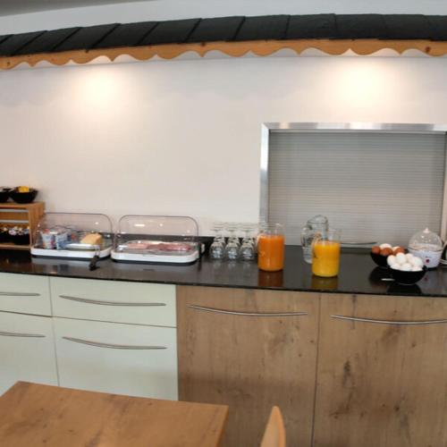 a kitchen with a counter with food and orange juice at Gästehaus Sonne in Bütschwil