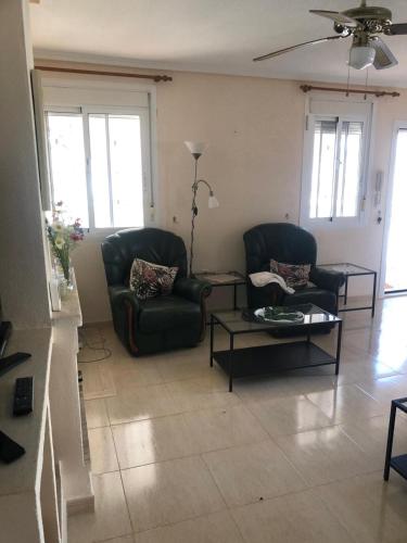 a living room with two chairs and a table at house with flowers in Gran Alacant