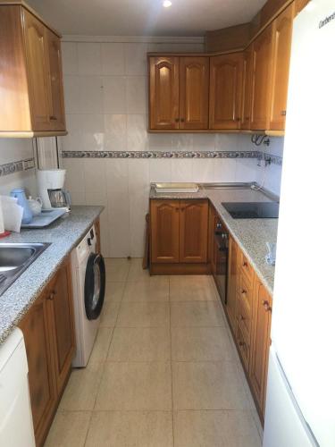 a small kitchen with wooden cabinets and a dishwasher at house with flowers in Gran Alacant