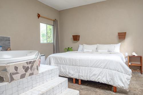 a bedroom with a large bed and a bath tub at Hokhmah Heart Hotel in Puerto Morelos