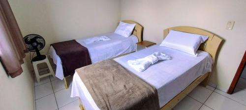 two beds in a hotel room with towels on them at Apartamento praia do morro in Guarapari