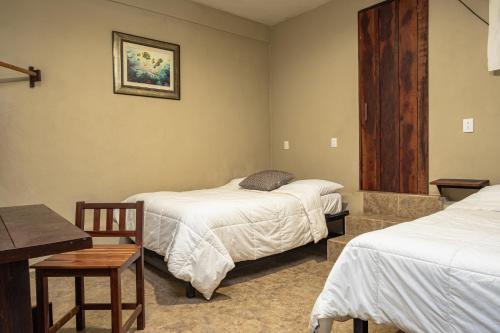 a room with two beds and a table and a desk at Hokhmah Heart Hotel in Puerto Morelos