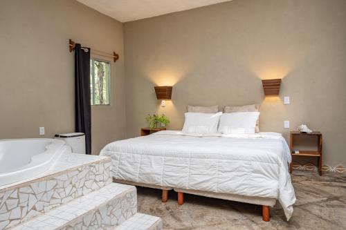 a bedroom with a large white bed and a tub at Hokhmah Heart Hotel in Puerto Morelos