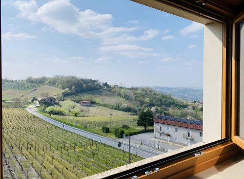 a window with a view of a road and vineyards at La Terrazza in Cassinasco