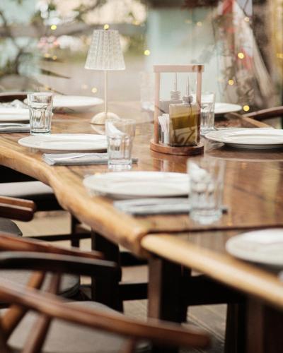a wooden table with plates and glasses and a lamp at Bianca Hotel & Villa in Tirana
