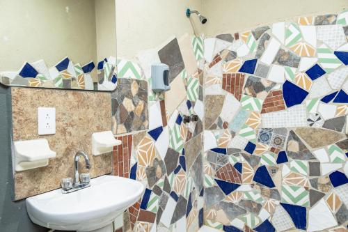 a bathroom with a sink and a mosaic tile wall at Hokhmah Heart Hotel in Puerto Morelos
