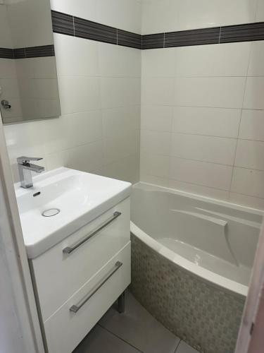 une salle de bain blanche avec un lavabo et une baignoire dans l'établissement Appartement vue mer CALIFORNIE PROMENADE DES ANGLAIS, à Nice