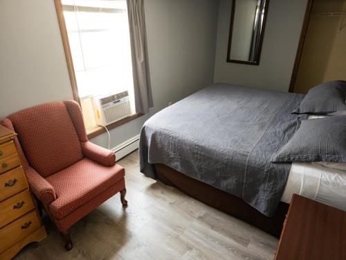 a bedroom with a bed and a chair and a window at Ships Inn in Hampton