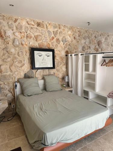 une chambre avec un lit avec un mur en pierre dans l'établissement Jolie maison avec vue sur piscine, à Bouc-Bel-Air