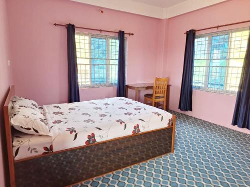 una camera da letto con un letto, un tavolo e finestre di Dipika Homestay Pokhara Apartment a Pokhara