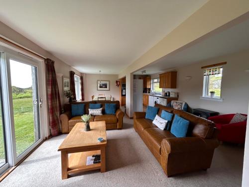 a living room with two couches and a table at Heather Cottage in Lairg