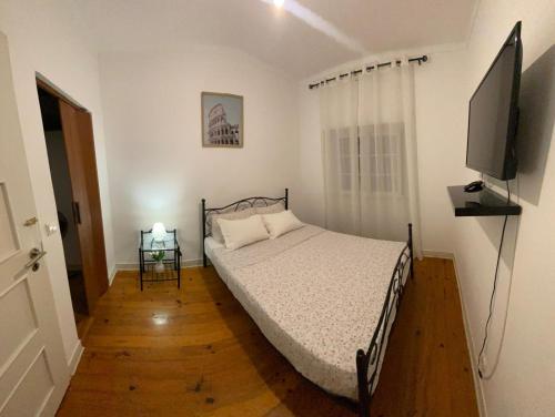 a bedroom with a bed and a flat screen tv at Travelers House in Setúbal