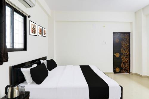 a white bedroom with a black and white bed at Super Hotel O Kadam Ghat Near Ashok RajPath in Patna