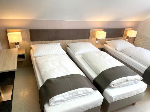 three beds in a room with lamps on the wall at Hana Aparthotel in Hamburg