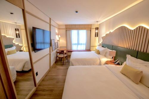 a hotel room with two beds and a mirror at DoubleTree by Hilton Caracol in Canela