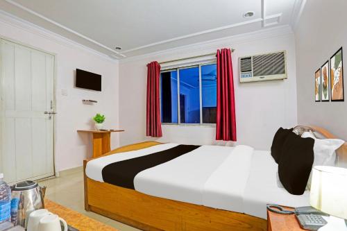 a bedroom with a bed with red curtains and a window at Super Hotel O Bhagalpur Railway Junction in Bhāgalpur