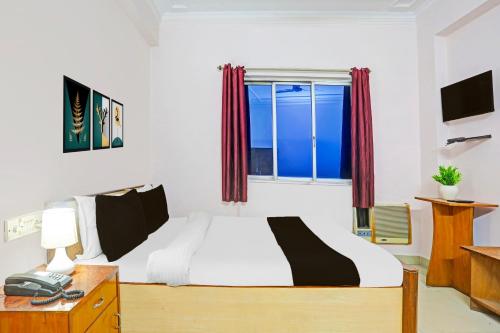 a bedroom with a bed and a desk and a window at Super Hotel O Bhagalpur Railway Junction in Bhāgalpur