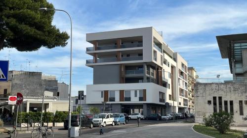 a tall white building with cars parked in front of it at Valesium Home in Lecce