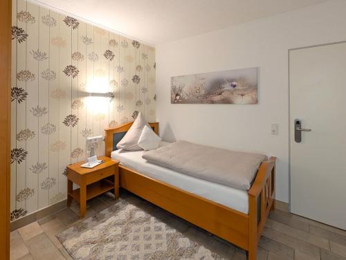 a small bedroom with a bed and a table at Hotel Maurer in Saarwellingen