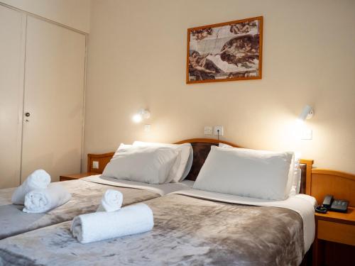 two beds in a hotel room with towels on them at Sappho Hotel in Skala Eresou