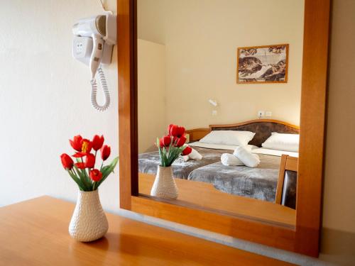 a mirror with two vases with flowers on a table at Sappho Hotel in Skala Eresou