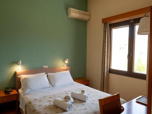 a bedroom with a bed with towels on it at Sappho Hotel in Skala Eresou