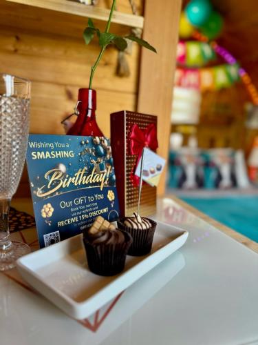 a plate with cupcakes and a gift box on a table at FINN VILLAGE - Loch Lomond Sunset Glamping Pod - Private Ofuro HOT TUB in Drymen