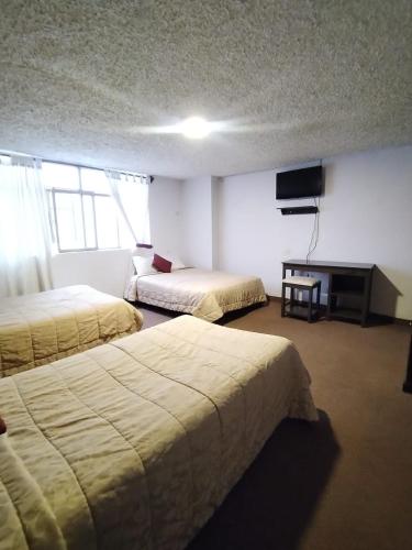 a hotel room with two beds and a television at Hotel Tomebamba Cuenca in Cuenca