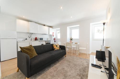 a living room with a black couch and a kitchen at Cruzeiro Charm Apartments in Lisbon