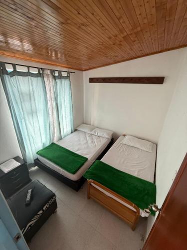 a small bedroom with two beds and a window at Hospedaje del Cafe Salento in Salento