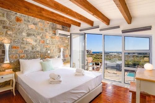 a bedroom with a bed and a stone wall at Villa Chloe Seastone by Villa Plus in Kiotari