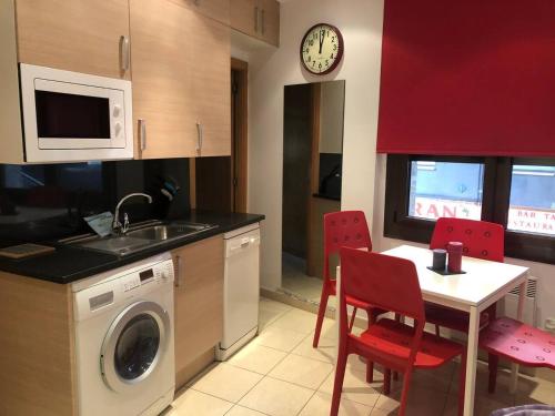 a kitchen with a washing machine and a table with red chairs at Sky 101 by Confortsky in Pas de la Casa