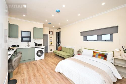 a bedroom with a white bed and a green chair at Stratford, London E15 - modern Studio for 3 in London