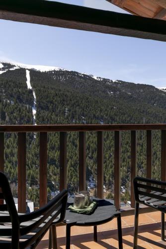 a table and chairs on a balcony with a view of a mountain at Luxury Summit Penthouse - Soldeu - By Ski Chalet Andorra in Soldeu