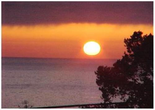 a sunset over the ocean with the sun at Snug Harbor in Cambria