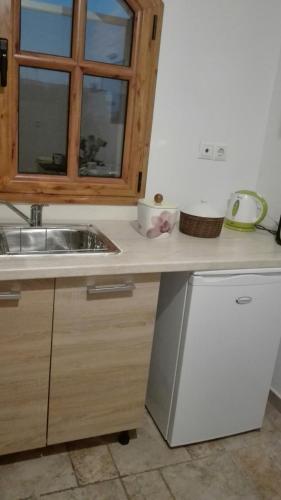 a kitchen counter with a sink and a window at House Under the Pines next to the sea in Mesochórion