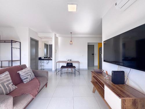 a living room with a couch and a large flat screen tv at Condomínio Residencial Unique Residence - São José do Rio Preto in Sao Jose do Rio Preto