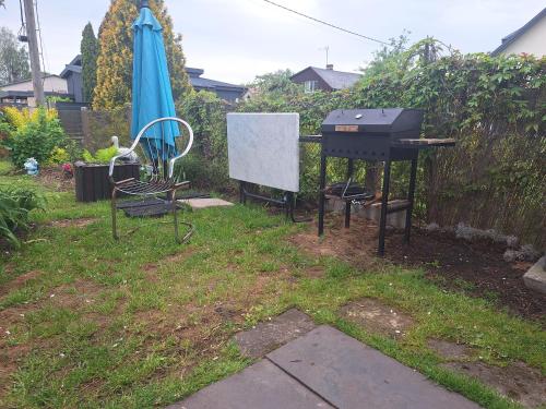 a grill and an umbrella in a yard at Ziedu aleja in Sigulda