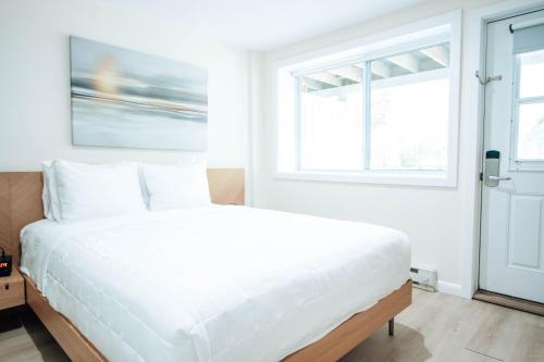 a white bed in a room with two windows at Sea Crest in Amagansett