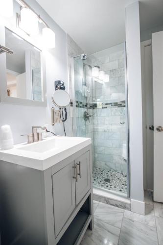 a white bathroom with a sink and a shower at Sea Crest in Amagansett