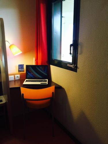 a laptop computer sitting on a desk with a window at Premiere Classe Nevers Varennes Vauzelles in Varennes Vauzelles