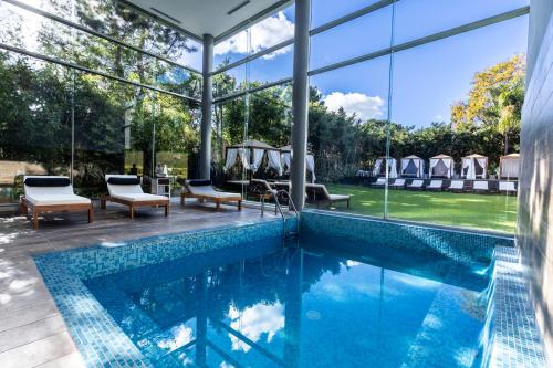 a swimming pool with glass walls and a patio with lounge chairs at Park Hotel in Punta del Este