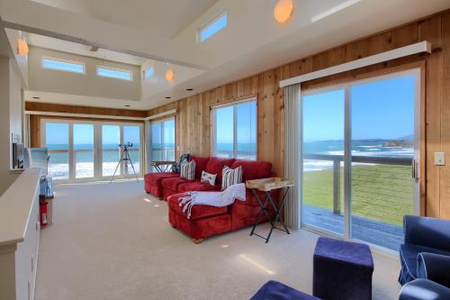a living room with a red couch and views of the ocean at Oceanfront Escape in San Simeon