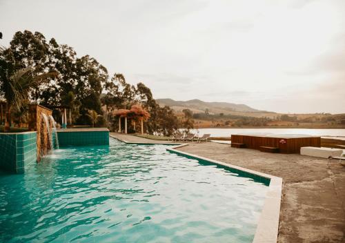 a swimming pool with a view of a body of water at Hotel Chalé Capitólio in Capitólio
