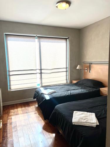 two beds in a room with two large windows at Precioso departamento en la mejor ubicación de Ciudad Mendoza, con piscina in Mendoza