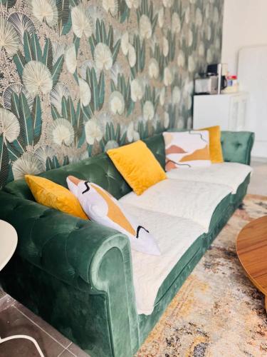 - un canapé vert avec des oreillers dans le salon dans l'établissement Loft Bis cosy proche des plages et villes, à Démouville