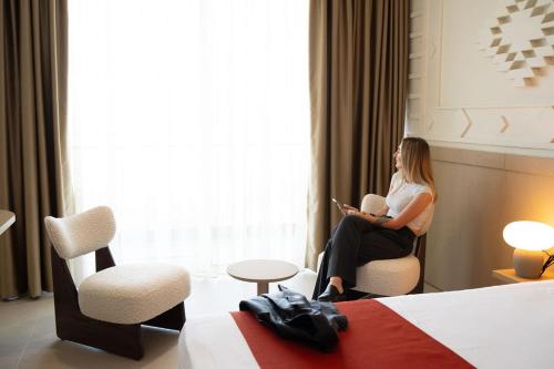 a woman sitting in a chair in a hotel room at Hotel Skanderbeg in Golem
